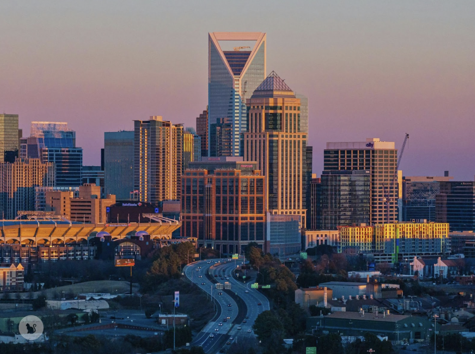 Charlotte skyline at sunset with Bank of America Corporate Center and city buildings glowing in golden light.